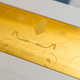 A close-up of the weighted brass medallion on the back of the Higround Summit 65 Gundam Wing keyboard.